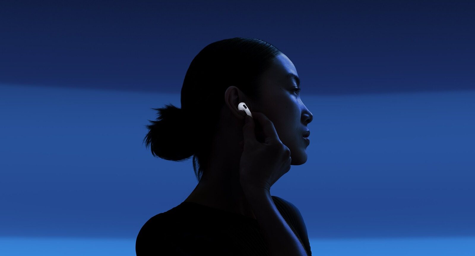 Žena se sluchátky AirPods 5 na modrém pozadí